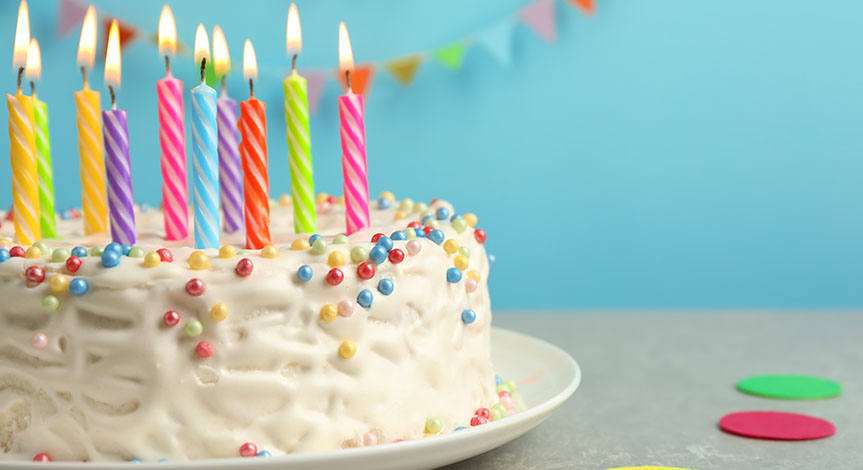 Delicious birthday cake with burning candles on table