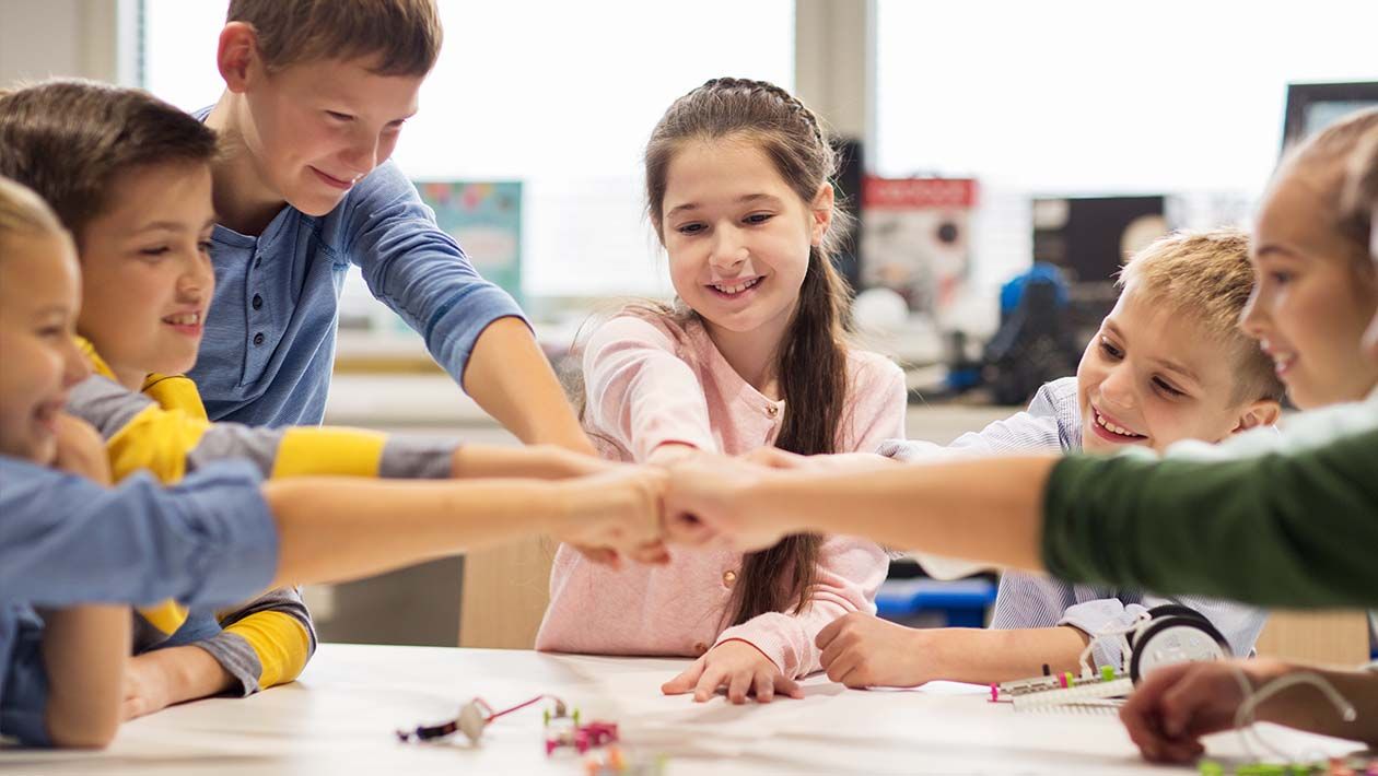 Group of kids building robots bumping fists